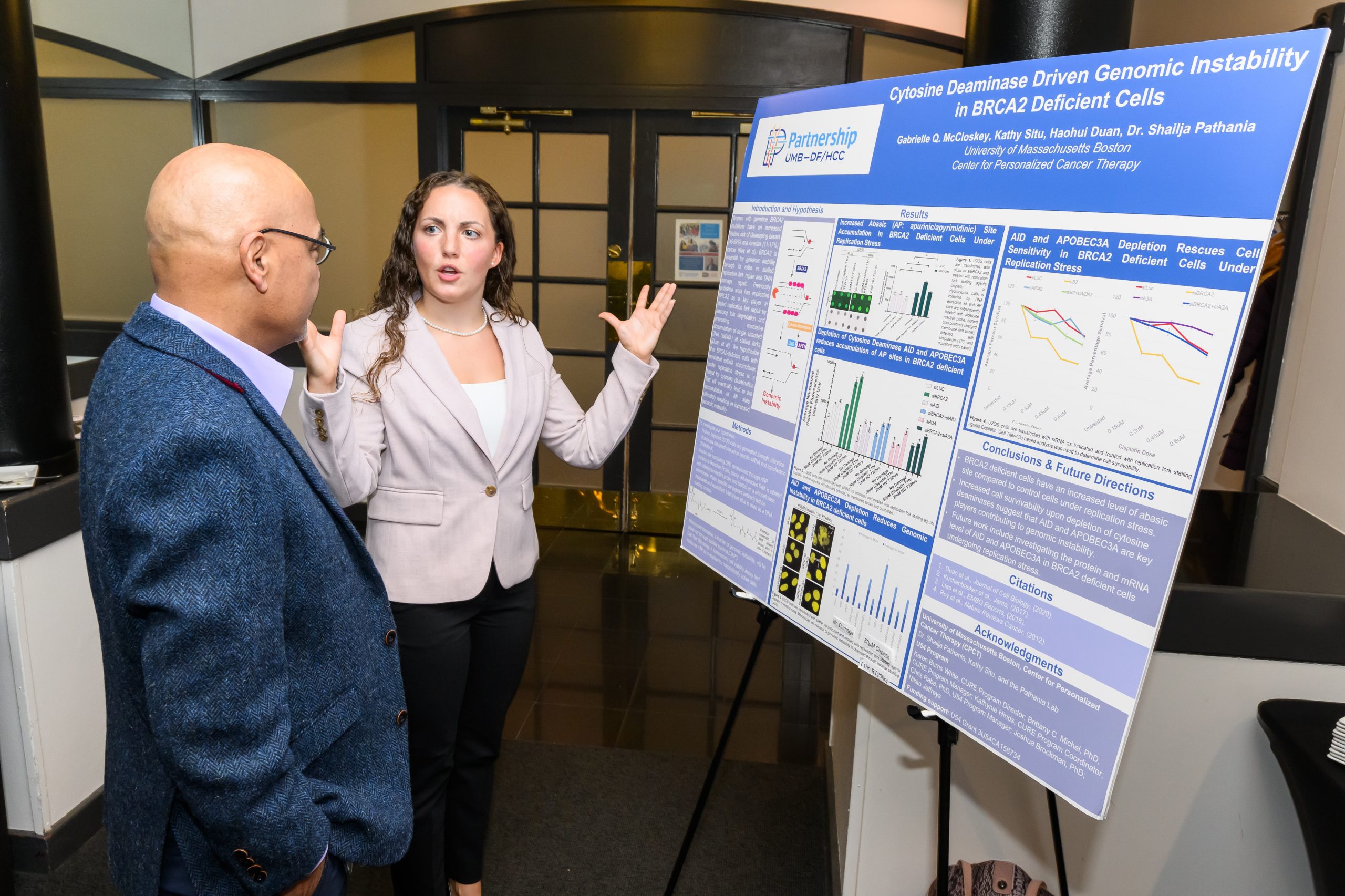 Trainee explains her research poster to a researcher.