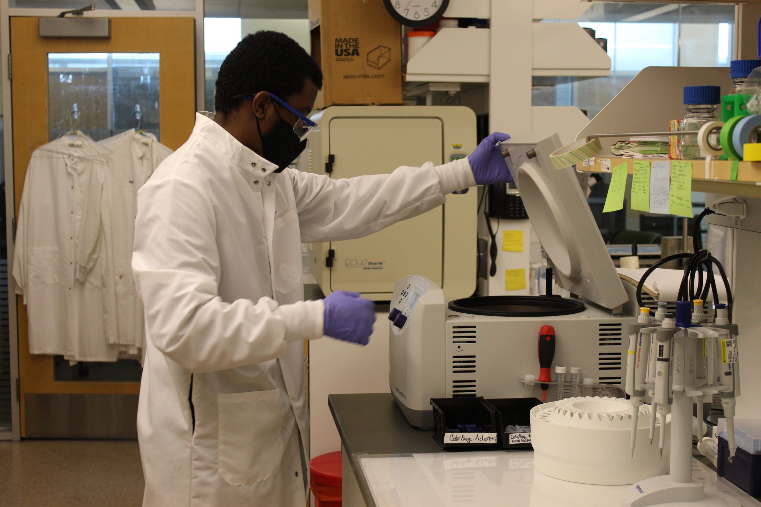 A trainee wearing a white coat and gloves uses genomics technology.