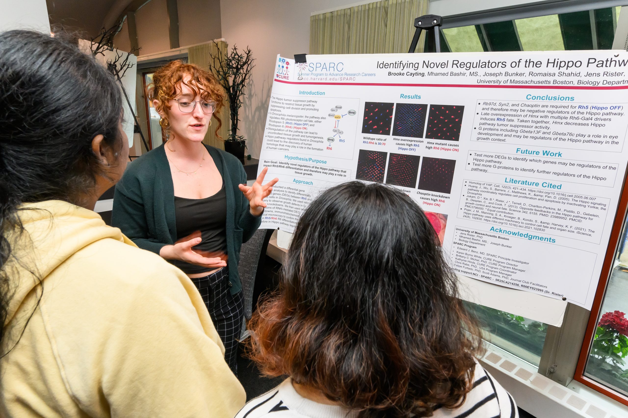 photo3 Trainee explains research poster to two listeners.